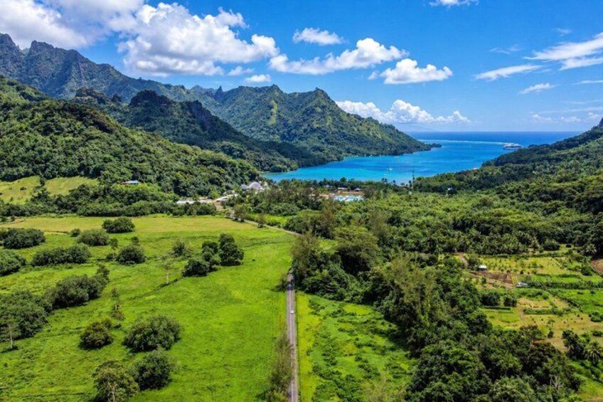 A mountainous landscape with a road, lush greenery, and a body of water. 3