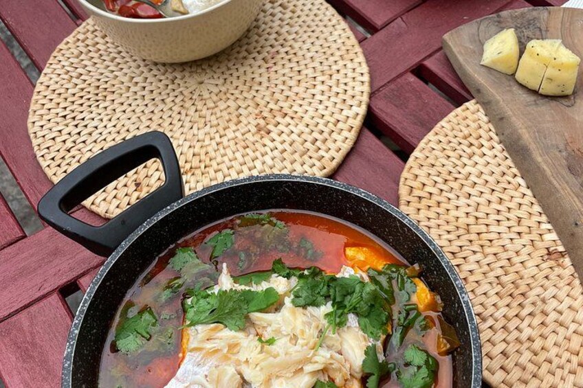 A bowl of soup with a black handle on a woven mat. 2