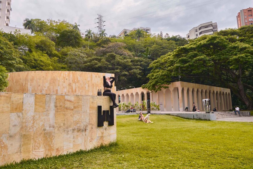 A park with a stone wall, a dog, and people sitting and walking. 4