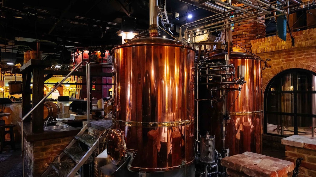 Copper stills in a brewery with brick walls and wooden barrels. 4