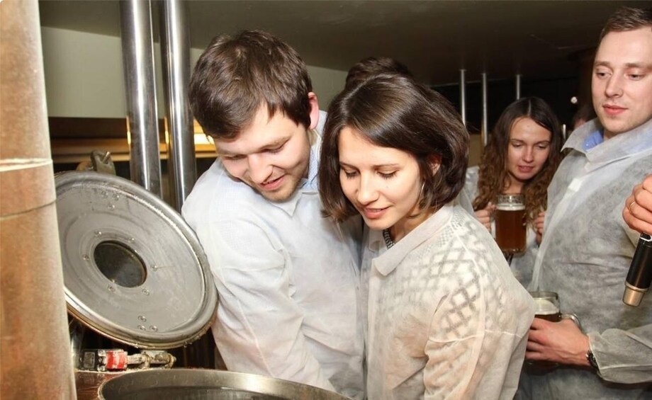 A group of people in a kitchen, some holding drinks. 5