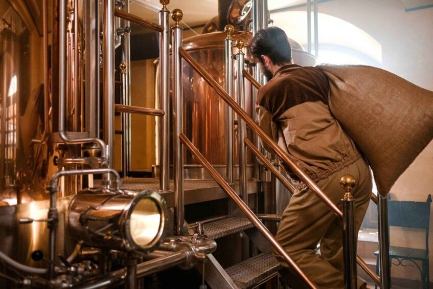 A person working in a brewery with copper tanks and equipment. 3