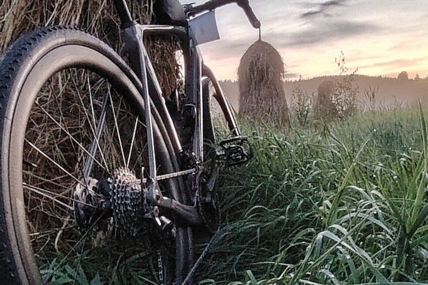 A bicycle in a grassy field with hay bales in the background. 5