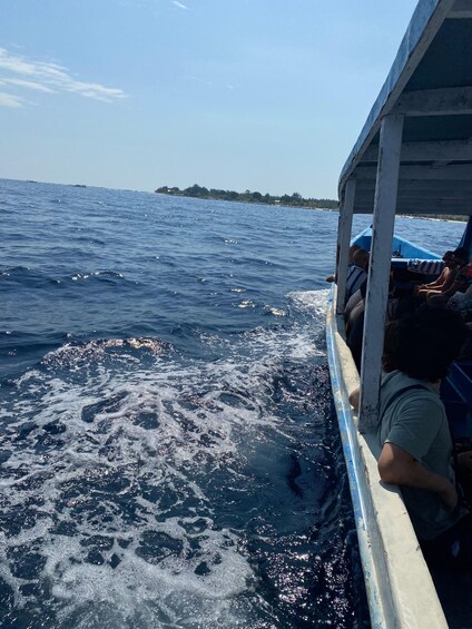A boat with people on board, water with waves, and a distant shoreline. 5