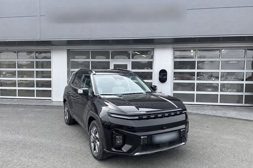 En sort SUV parkeret foran en bygning med en garageport. 1