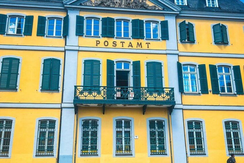 A yellow building with green shutters and the word 'POSTAMT' on the facade. 2