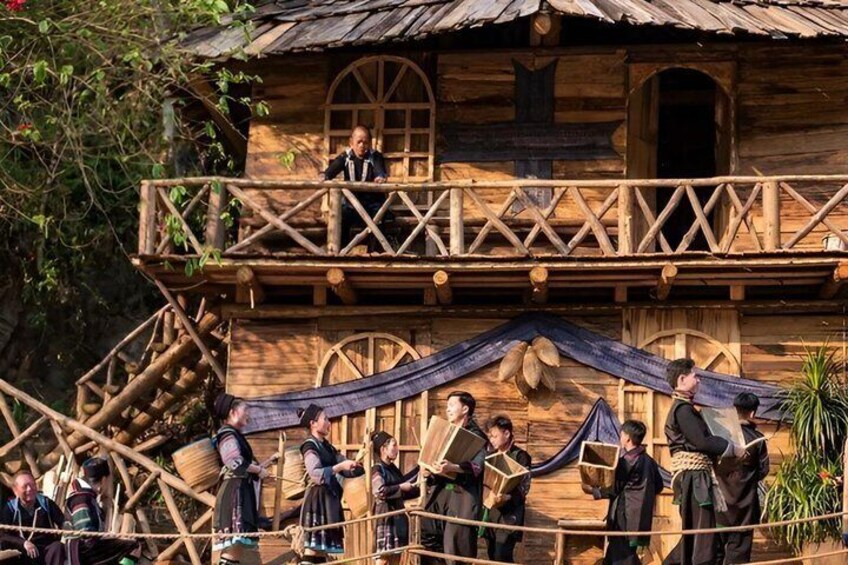 A wooden building with a balcony, people in period costumes, and a rope. 5