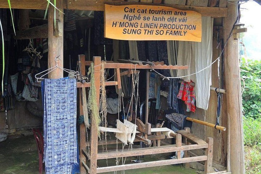 A traditional loom with hanging textiles, a signboard, and a rustic wooden structure. 2