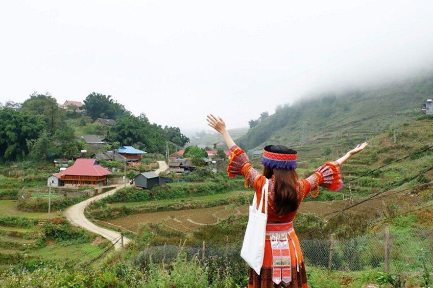 A person standing on a hill overlooking a village with houses and greenery. 1