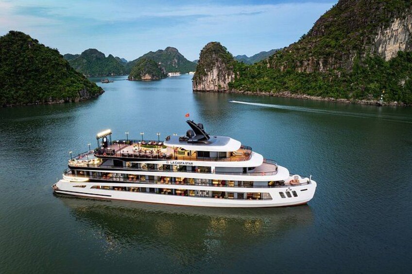 Un gran crucero de varias cubiertas llamado 'La Costa Star' navega por un río tranquilo rodeado de exuberantes colinas verdes. 4