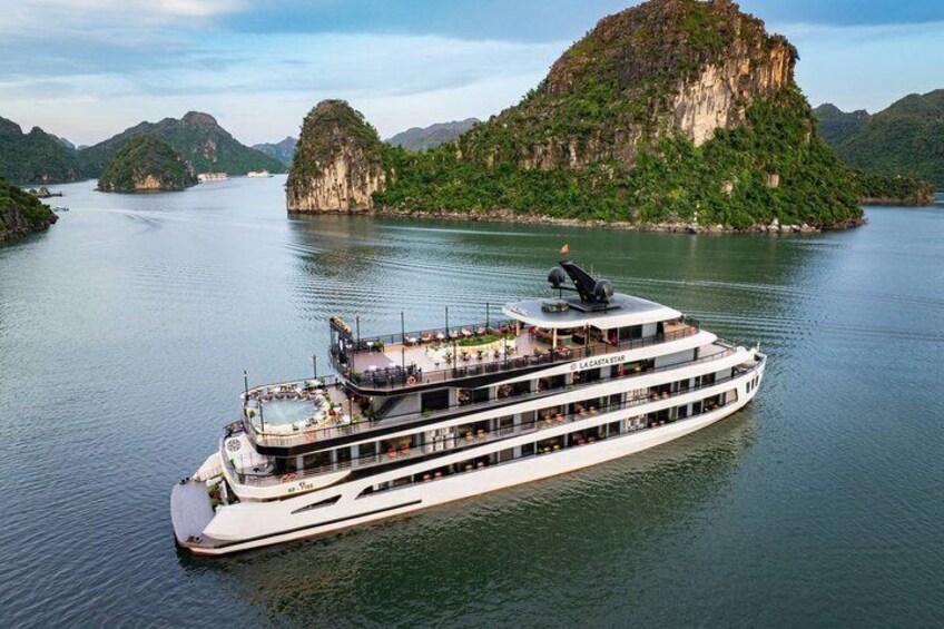Un barco de crucero fluvial con varias cubiertas y un paisaje montañoso al fondo. 1