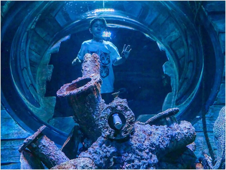 A person inside a large, cylindrical structure with rusted metal and a blue light. 1