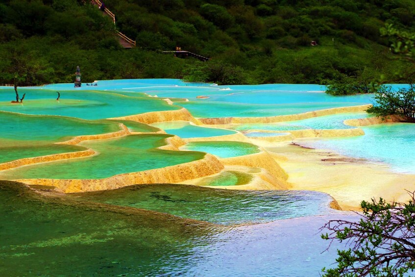 Terraced pools of turquoise and yellow hues, surrounded by lush greenery. 4