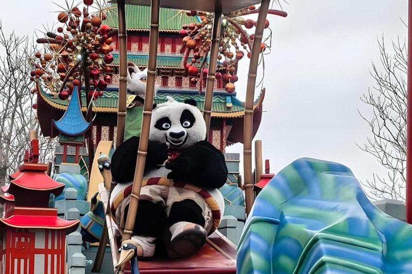 A panda mascot on a ride, traditional Chinese architecture, and colorful decorations. 4