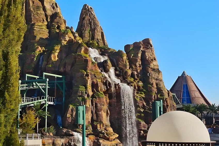 A waterfall cascading down a rocky cliff, a green observation platform, and a large dome structure. 2
