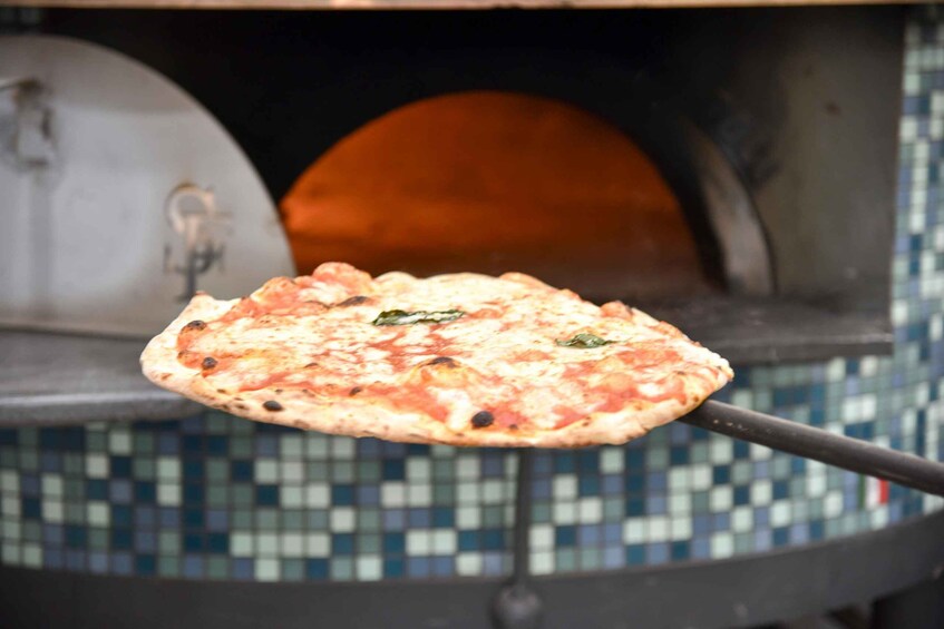 A pizza being removed from a brick oven. 5