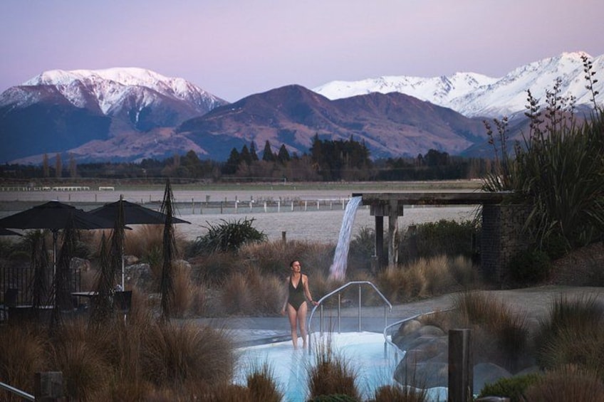 A person in a swimsuit by a hot spring with a mountain backdrop. 1