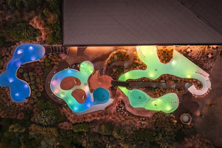 An aerial view of a landscaped area with multiple swimming pools and a building. 2