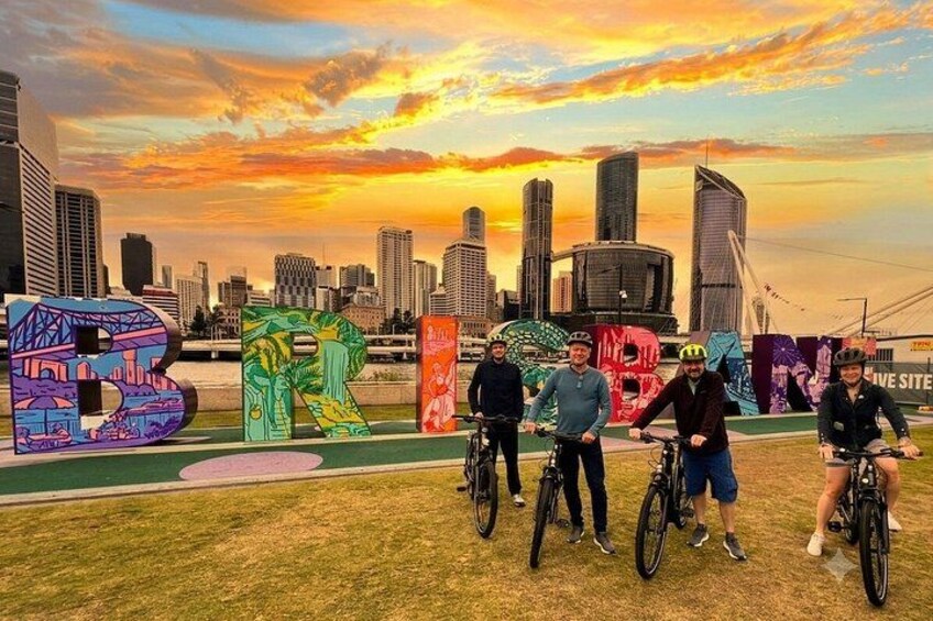 A group of cyclists in a city park with a sunset and skyscrapers in the background. 5