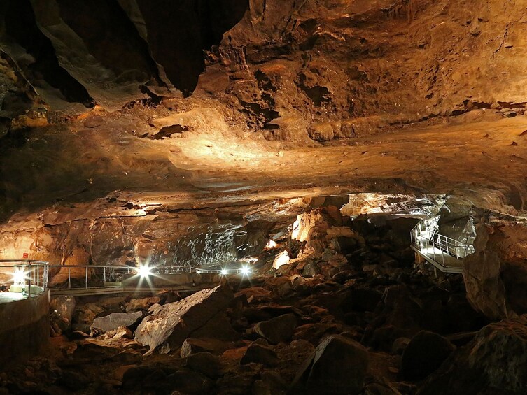 A cave with illuminated rock formations and a walkway. 3