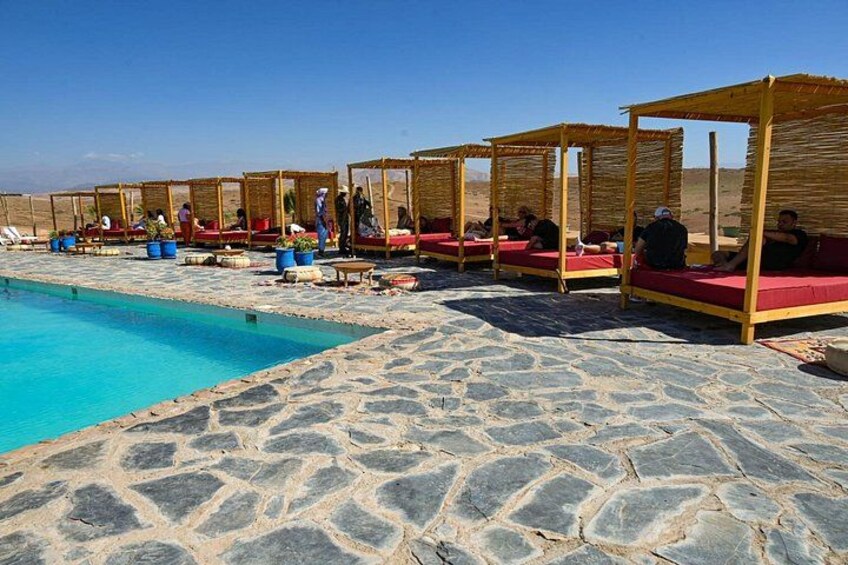 A poolside area with stone flooring and wooden canopies. 1