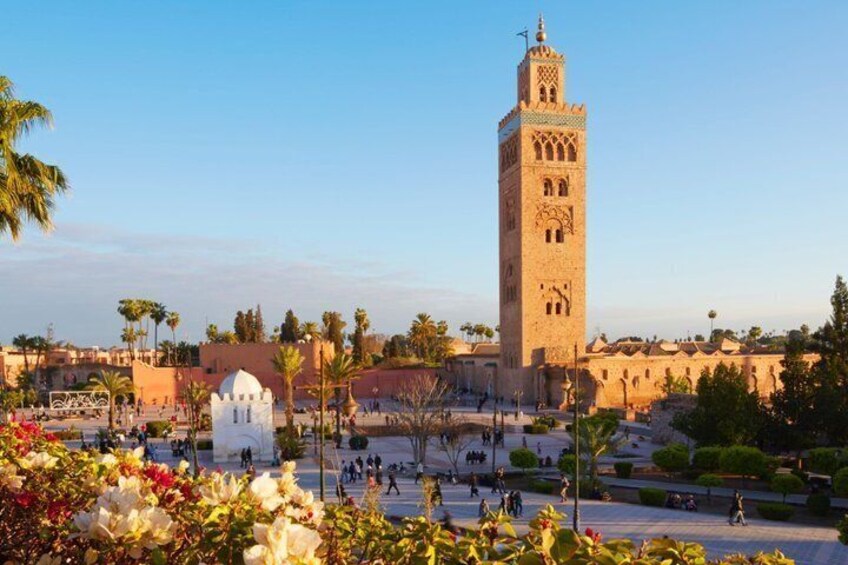 A historic tower, a mosque, and a bustling square with palm trees. 3