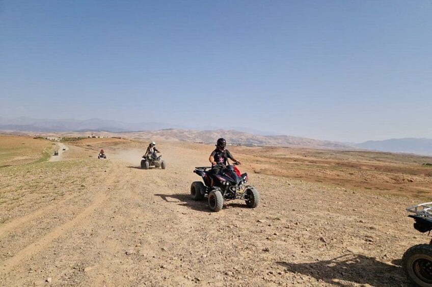 A group of people riding ATVs on a dirt road in a desert landscape. 2