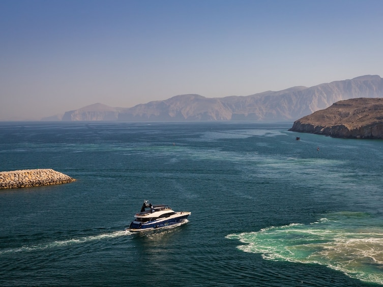 A boat on a calm sea with rocky cliffs in the background. 3