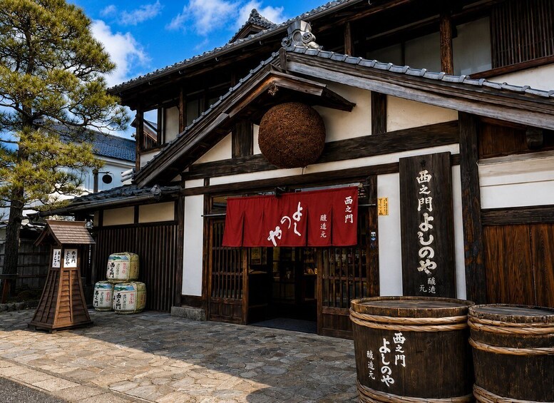 A traditional Japanese building with a red banner, wooden barrels, and a stone-paved entrance. 4