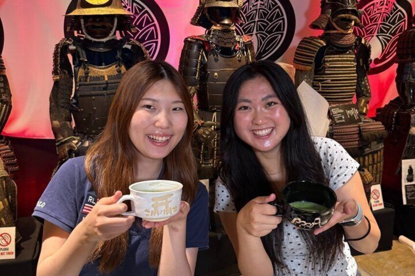 Two people holding mugs in front of a display of armor and helmets. 4