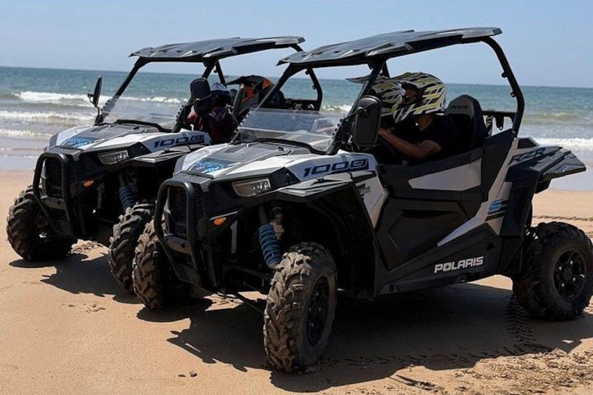 Three Polaris 1000 ATVs parked on a sandy beach with the ocean in the background. 4