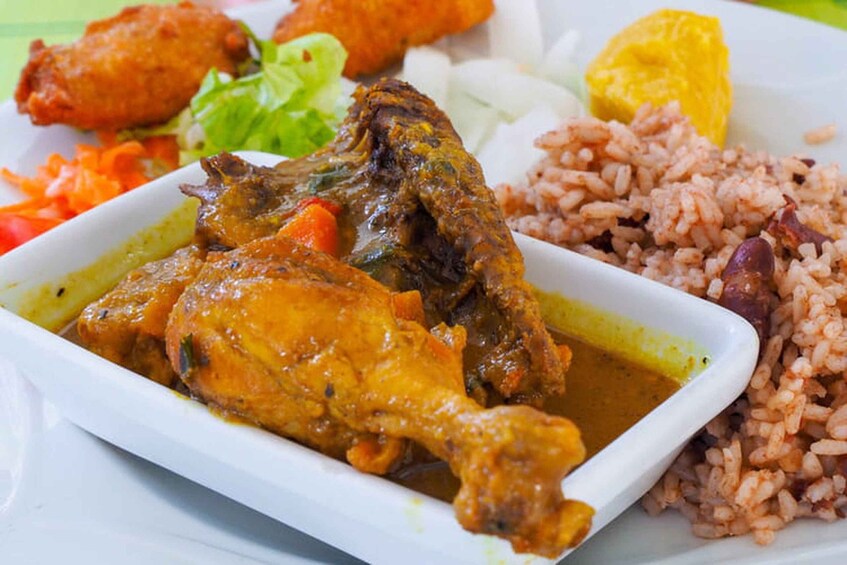 A plate of chicken curry, rice, and vegetables. 4