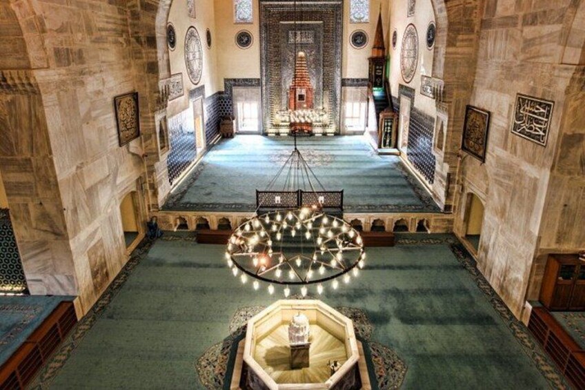 A mosque interior with a central dome, arched ceilings, and patterned walls. 5
