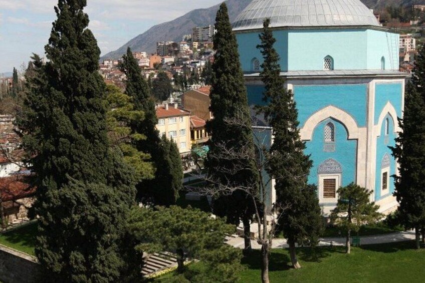 A blue building with arched windows, surrounded by trees and a cityscape in the background. 4
