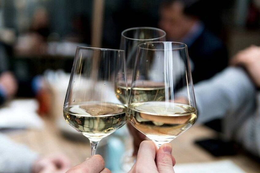 Two people holding wine glasses with a blurred background of other people. 4