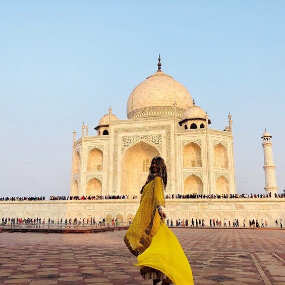 Taj Mahal -monumentti, ja sen edessä kävelee keltaisessa mekossa oleva henkilö. 3