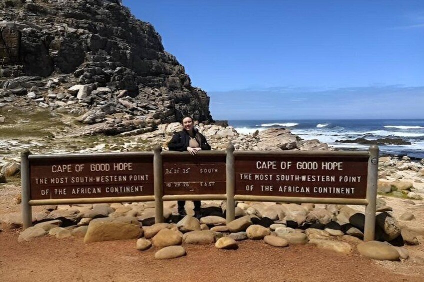 A sign at Cape of Good Hope, the most southwestern point of the African continent, with a rocky coastline and ocean in the background. 2