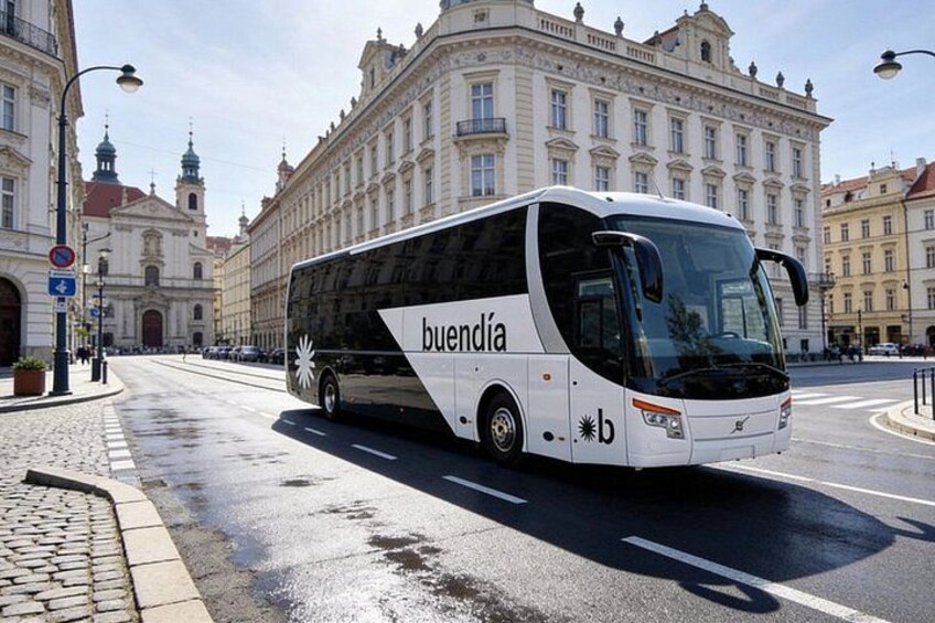 A white bus with 'buendia' branding on a city street. 2
