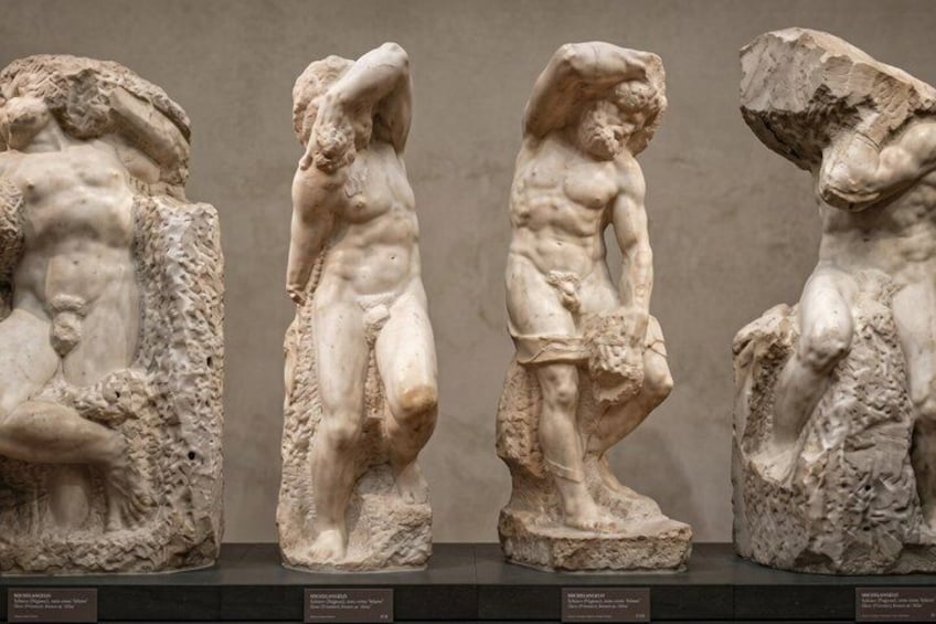 Three classical marble sculptures of male figures in dynamic poses, displayed on pedestals. 5