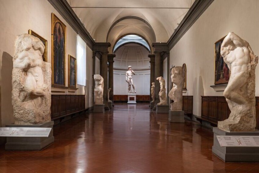 A museum corridor with classical sculptures and paintings. 2