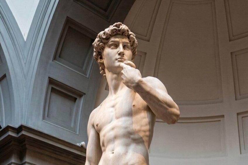 A marble statue of a muscular figure with a thoughtful expression, set against a classical architectural backdrop with geometric patterns. 1