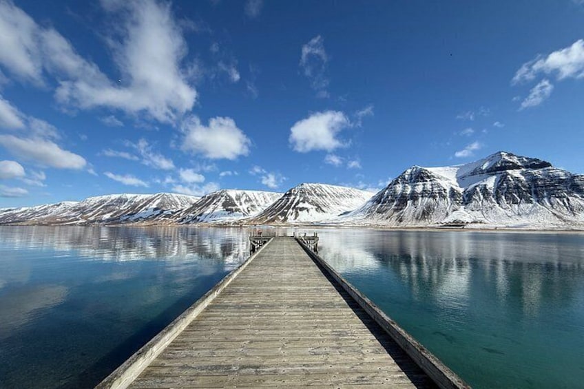 A wooden pier extending into a calm lake with snow-capped mountains in the background. 5