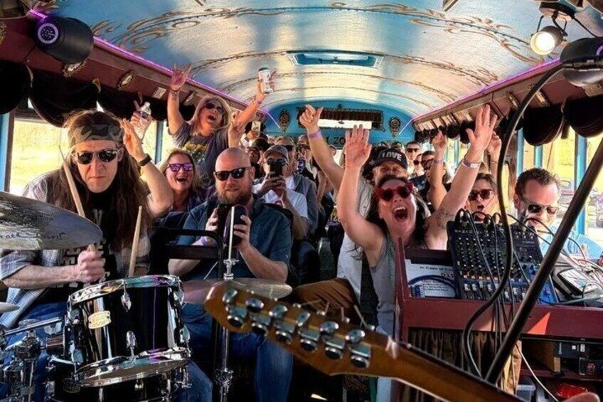 A band performing inside a bus with a crowd cheering. 1