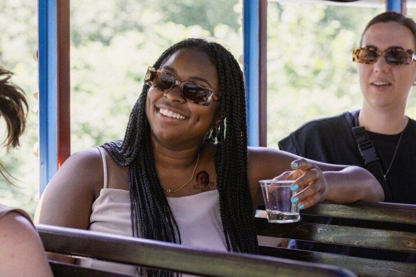A person sitting at a table with a drink, outdoors with trees in the background. 4