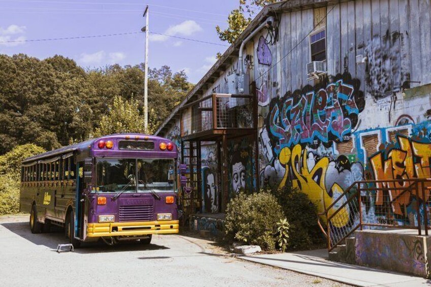 A purple and yellow bus parked in front of a building with graffiti. 5