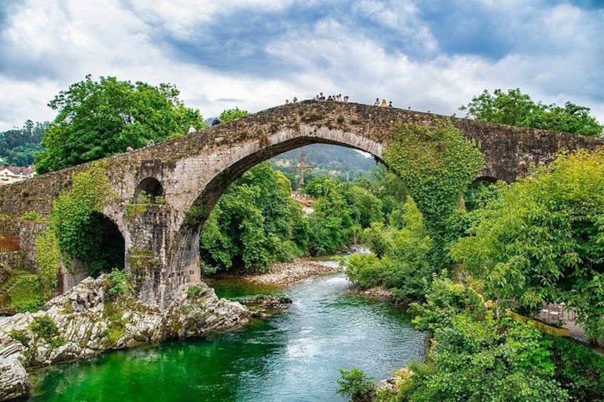 A stone bridge over a river, surrounded by lush greenery and trees. 3