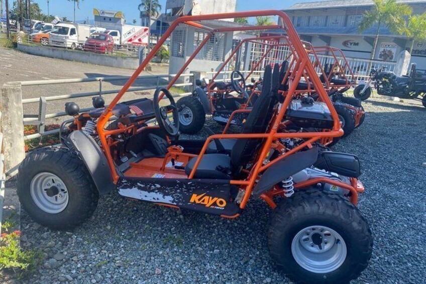 An orange off-road vehicle with 'Kayo' branding parked on gravel. 3