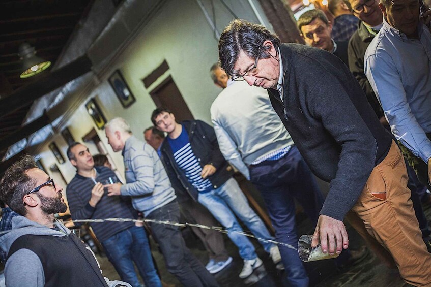 A group of people in a crowded indoor setting with visible brick walls and wooden beams. 5