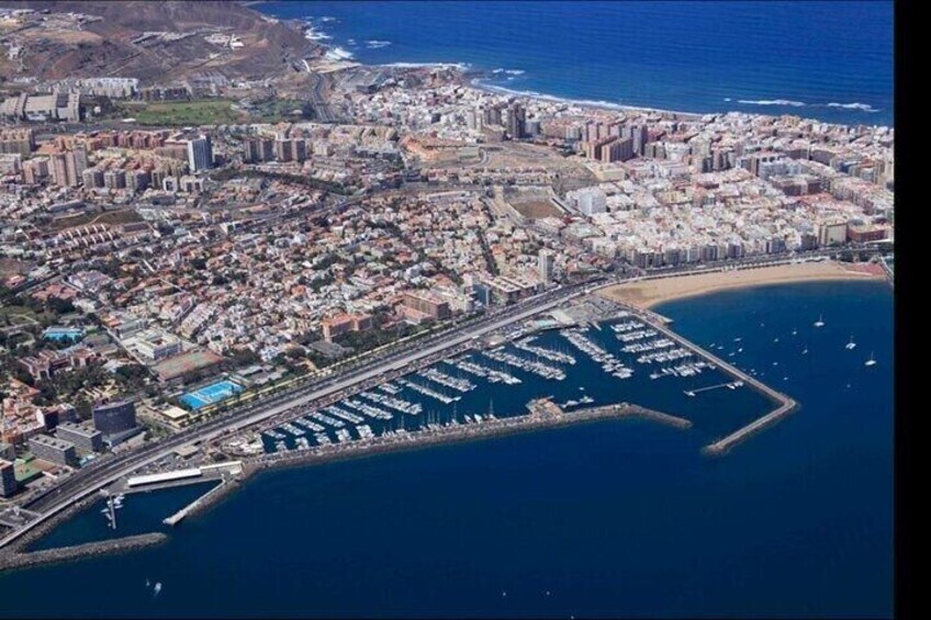 An aerial view of a coastal city with a marina, dense urban area, and a beach. 2