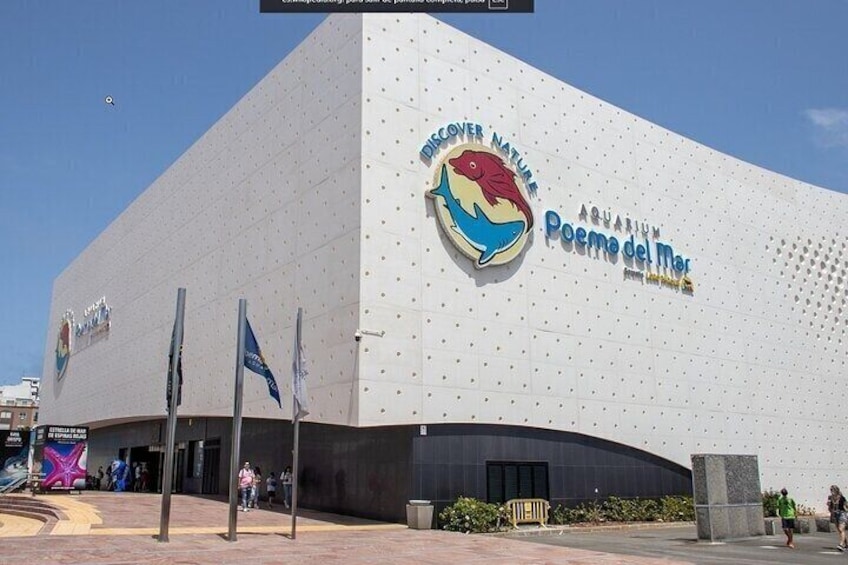 A modern building with a large aquarium sign, featuring a colorful fish logo. 4